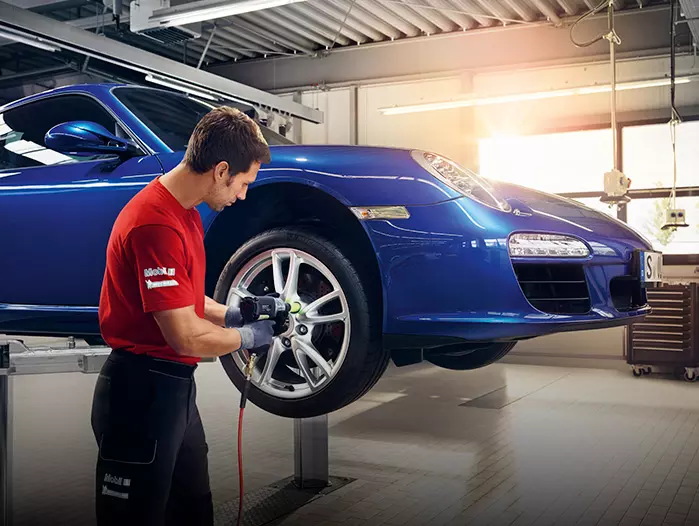 Mecánico cambia la rueda a un Porsche